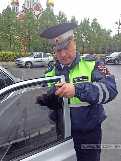 Рейд «Таксист» прошел в Одинцово, сотрудник ГИБДД проверяет тонировку стекла